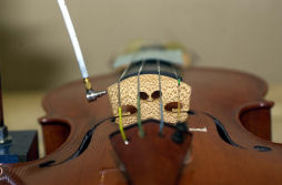 The miniature force hammer used to transmit an impulse to the violin bridge